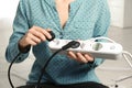 Woman inserting power plug into extension cord indoors, closeup. Electrician`s