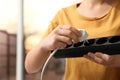 Woman inserting power plug into extension cord indoors, closeup.