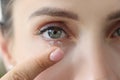 A woman inserts a contact lens into her eye, close-up