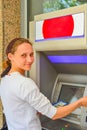 A woman inserts a plastic card into an ATM for withdrawing cash