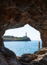 Woman inside cave, view Lighthouse Portocolom in Mallorca.