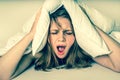 Woman with insomnia covering head and ears with pillow