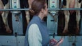 Woman inspect milking equipment hold tablet computer in modern parlour closeup.