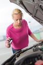 Woman inspecting broken car engine. Royalty Free Stock Photo