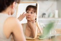 Woman inspecting facial skin in mirror during daily routine