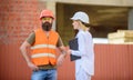 Woman inspector and bearded brutal builder discuss construction progress. Construction project inspecting. Safety