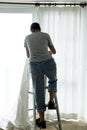 A woman installing window curtain