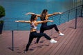 Woman instructor workout with young woman on promenade by riv