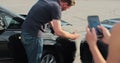 Woman insurance agent inspects damage to a man car and makes notes on a smartphone. Woman inspecting broken car Royalty Free Stock Photo