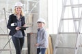 Woman interior designer or architect mom with her son at work, they choose how to furnish the house, inside the construction site Royalty Free Stock Photo