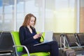 Woman in international airport terminal, checking her phone Royalty Free Stock Photo