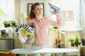 Woman with iron and clothes basket in modern house in sunny day Royalty Free Stock Photo