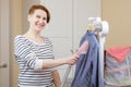 Woman ironing a striped business shirt with a handheld garment steamer Royalty Free Stock Photo