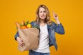 Woman isolated on orange background. Delivery service from shop or restaurant concept. Hold brown craft paper bag for