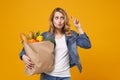 Woman isolated on orange background. Delivery service from shop or restaurant concept. Hold brown craft paper bag for