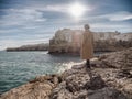 Woman isolated on the rocks looking Polignano a mare in winter season