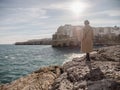 Woman isolated on the rocks looking Polignano a mare in winter season