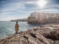 Woman isolated on the rocks looking Polignano a mare in winter season