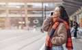 woman in jacket and orange scarf waiting for a tram at the stop and talking on pnone Lifestyle photo Royalty Free Stock Photo