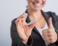 A woman in a jacket shows her thumbs up and demonstrates mouth guards to align the bite. The girl approves of the