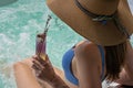 Woman in jacuzzi hot tub in blue bikini holding cocktail glass