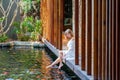 Woman on wooden bridge in Japanese garden feeding fish Royalty Free Stock Photo