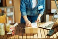 Woman in jeans applying shipping label to parcel in warehouse