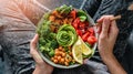 Woman in jeans holding Buddha bowl with salad, baked sweet potatoes, chickpeas, broccoli, greens, avocado, sprouts in hands. Royalty Free Stock Photo