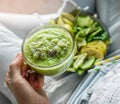 Woman in jeans holding fresh green smoothie with sesame, kiwi, apple, cucumber on light background. Healthy food, clean eating, Royalty Free Stock Photo