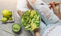 Woman in jeans holding fresh healthy greeen salad with avocado, kiwi, apple, cucumber, pear, greens and sesame on light background Royalty Free Stock Photo