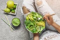 Woman in jeans holding fresh healthy green salad with avocado, kiwi, apple, cucumber, pear, greens and sesame on light background Royalty Free Stock Photo