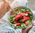 Woman in jeans holding fresh summer watermelon salad with feta cheese, arugula, spinach and greens on light background. Healthy Royalty Free Stock Photo