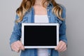 Woman in jeans shirt holding digital table with blank black screen for text. he is isolated on grey background pad pda advertising