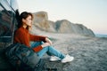 woman in jeans and sneakers sits on the sand near the car in nature Royalty Free Stock Photo