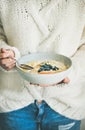 Woman in jeans and sweater eating oatmeal porriage with berries Royalty Free Stock Photo