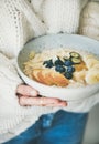 Woman in jeans and sweater holding bowl of oatmeal porriage Royalty Free Stock Photo