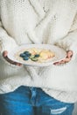 Woman in jeans and sweater holding plate of oatmeal porriage Royalty Free Stock Photo