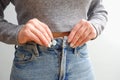A woman in jeans and a top fastens a jeans button. cropped shot of young woman buttoning up her jeans Concept of excessive weight