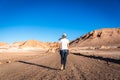 Woman in a jeans walking in the middle of the road in a stunning landscape in the Moon valley valle de la luna in Atacama Desert