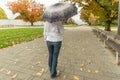 Woman in jeans walking with an umbrella in the rain in an autumn