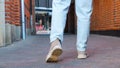 A woman in jeans walks through the narrow streets of the old city. Cropped photo back view of legs. Brick walls around the Royalty Free Stock Photo