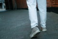 A woman in jeans walks through the narrow streets of the old city. Cropped photo back view of legs. Brick walls around the Royalty Free Stock Photo