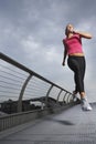 Woman jogging on foot bridge low angle view Millennium Bridge London England