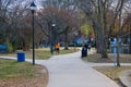 A woman jogging in an orange jacket on a smooth footpath in the park with other people on the footpath