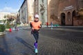 Woman jogging on rome street with smartphone and headphones