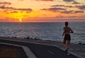 A woman jogging at sunrise on the coast, Caleta de Fuste, Fuerteventura, Canary Islands, Spain