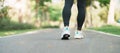 woman jogging and walking on the road at morning, Young adult female in sport shoes running in the park outside, leg muscles of Royalty Free Stock Photo