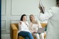 Woman with journal talk over work standing in front of brunette and preggers blonde that sitting on sofa and laughing. Royalty Free Stock Photo