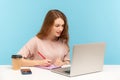 Woman journalist working on laptop and making notes on paper. Student studying, writing in notebook Royalty Free Stock Photo