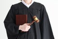 Woman judge in classic gown holds book and wooden mallet